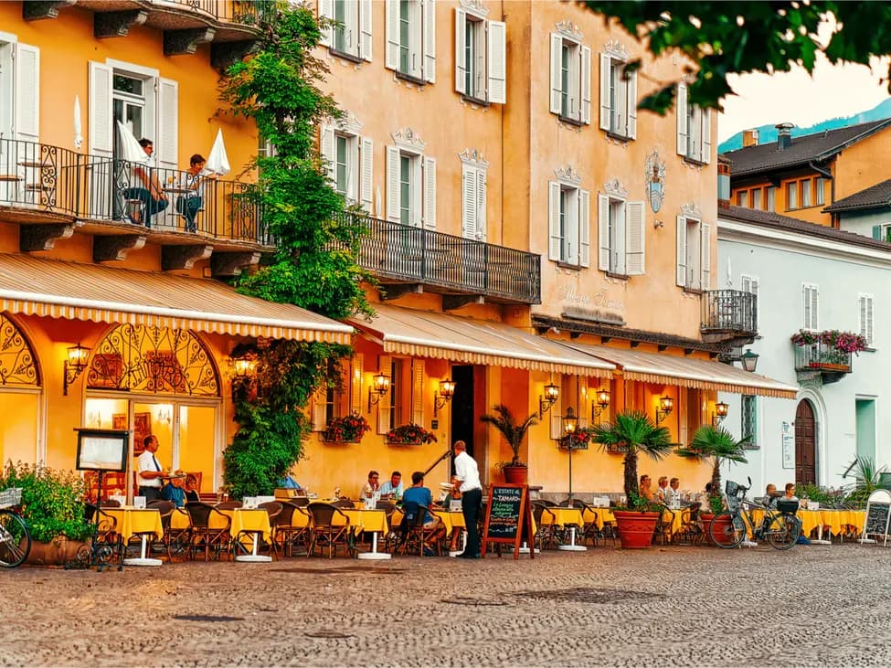 Restaurant in Ascona with guests on the terrace, surrounded by plants and warm light