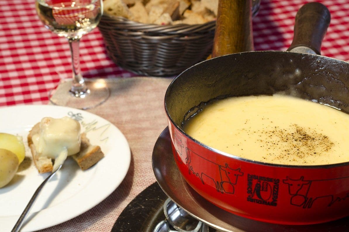 Fondue with melted cheese and side dishes on a table