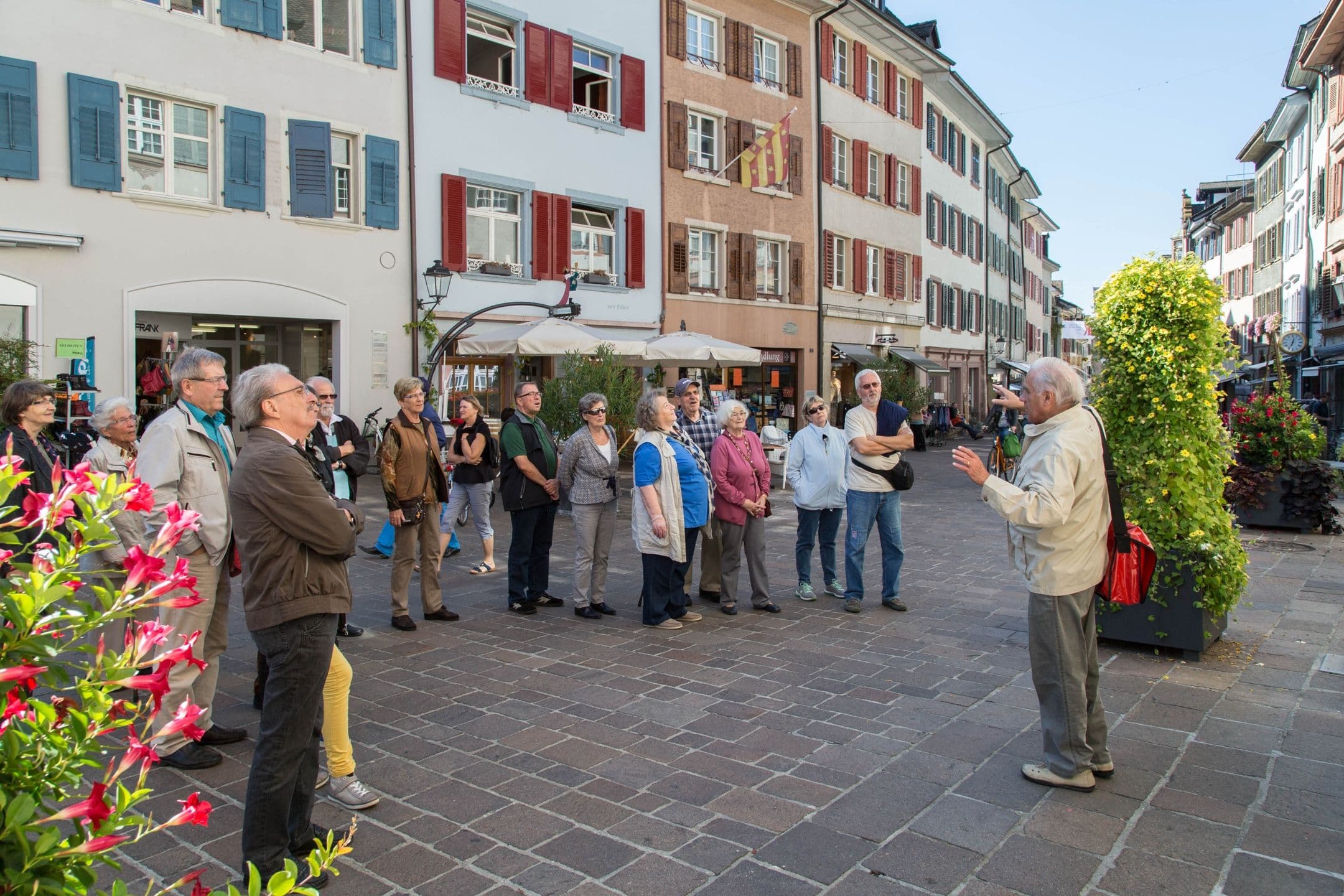 Rheinfelden city tour, visitors listening to a narration, old buildings, flowers